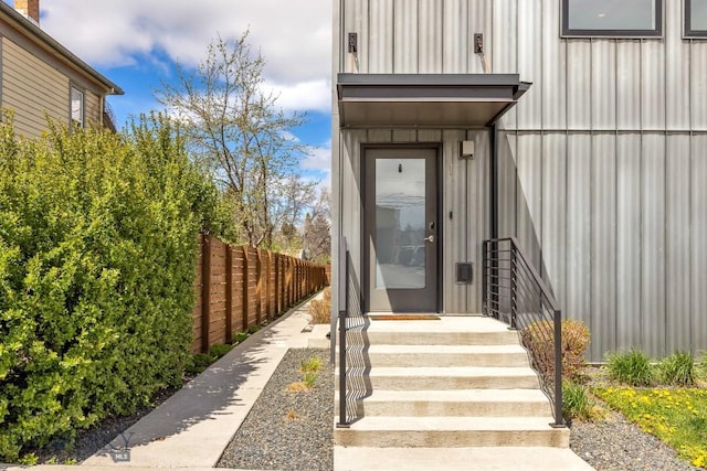 property entrance featuring board and batten siding and fence