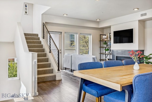 dining room with wood finished floors, stairway, a glass covered fireplace, recessed lighting, and baseboards