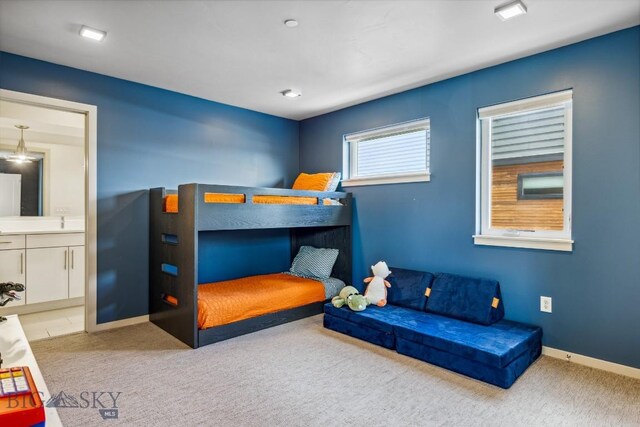 carpeted bedroom with connected bathroom and baseboards