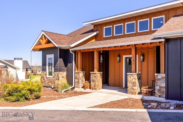 view of front of property featuring board and batten siding, stone siding, roof with shingles, and a porch