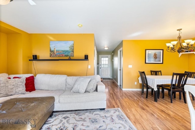 living area featuring a chandelier, light wood-style flooring, and baseboards