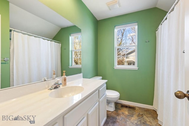 bathroom featuring vaulted ceiling, toilet, stone finish flooring, vanity, and baseboards