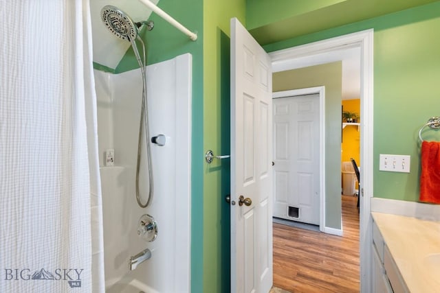 bathroom with wood finished floors, shower / bathtub combination with curtain, and vanity