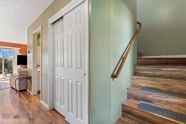 stairway with wood finished floors and a textured ceiling