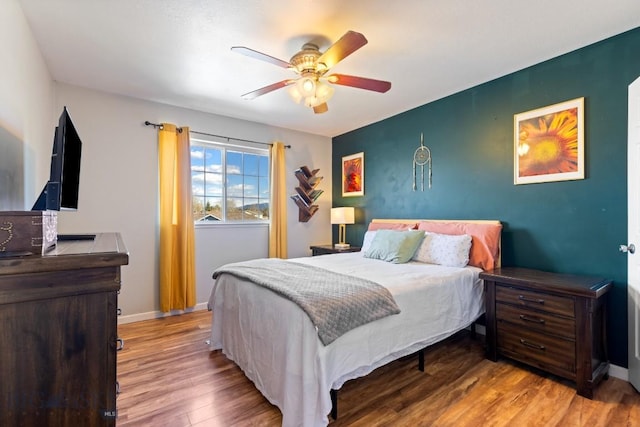 bedroom featuring wood finished floors, a ceiling fan, and baseboards