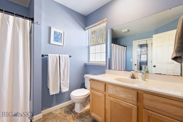 bathroom with healthy amount of natural light, baseboards, toilet, and vanity