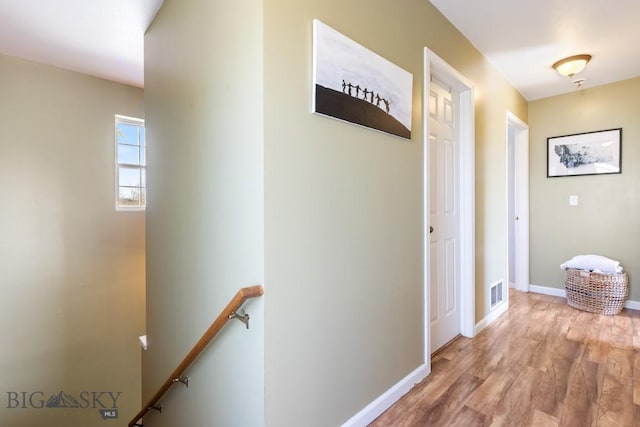 hallway featuring an upstairs landing, wood finished floors, and baseboards