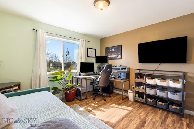 bedroom featuring wood finished floors and an office area
