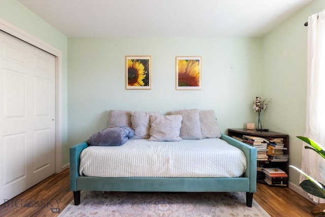 bedroom with wood finished floors, a closet, and baseboards