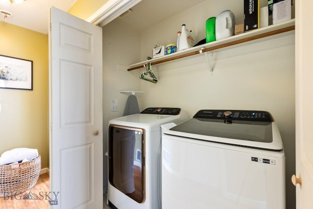 clothes washing area with washer and dryer and wood finished floors