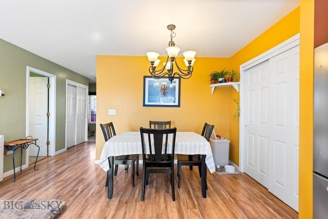 dining space with a chandelier, light wood-style floors, and baseboards