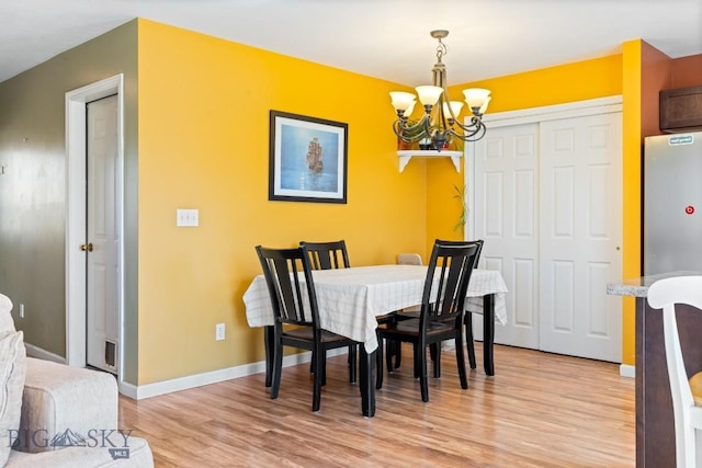 dining space with a chandelier, light wood-type flooring, and baseboards