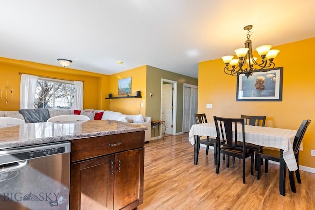 kitchen featuring dishwasher, a chandelier, open floor plan, light wood-style floors, and baseboards