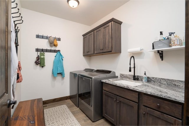 laundry area with washer and dryer, cabinet space, baseboards, and light wood-style floors