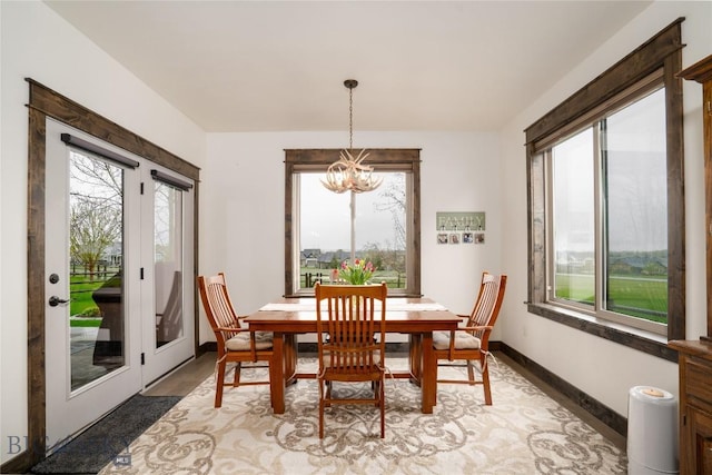 dining room with a chandelier, healthy amount of natural light, baseboards, and light wood finished floors