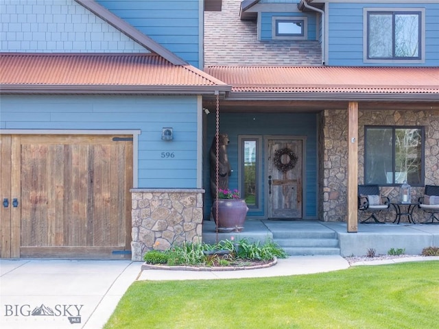view of exterior entry with a porch, stone siding, and metal roof