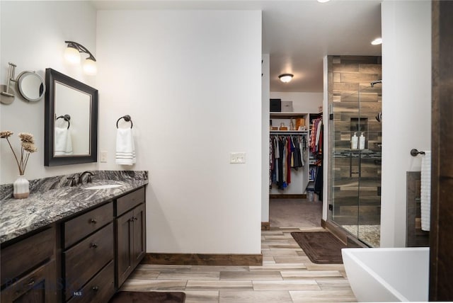 bathroom featuring a shower stall, wood tiled floors, vanity, a soaking tub, and recessed lighting