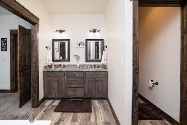 full bath with wood finished floors, double vanity, and baseboards