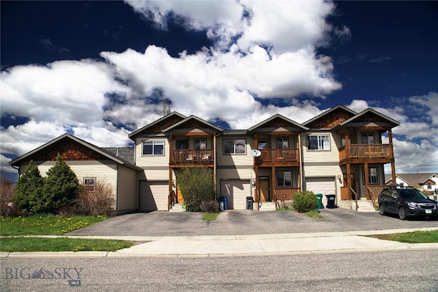 view of front facade with an attached garage, a balcony, and driveway