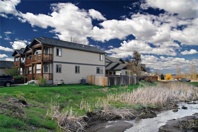 back of property with a balcony, fence, and central AC unit