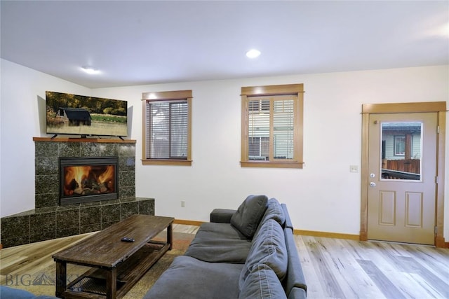 living room featuring wood finished floors, a tile fireplace, baseboards, and recessed lighting