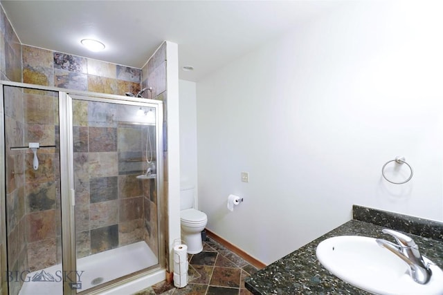 bathroom with a sink, a shower stall, toilet, and baseboards