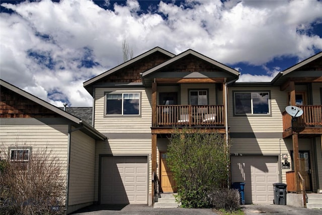 view of front facade with a balcony, an attached garage, and asphalt driveway
