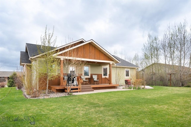 back of house featuring a lawn, board and batten siding, roof with shingles, and a deck