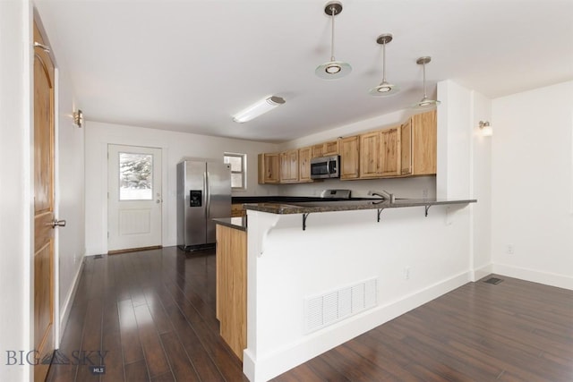 kitchen featuring stainless steel appliances, dark countertops, baseboards, and a peninsula