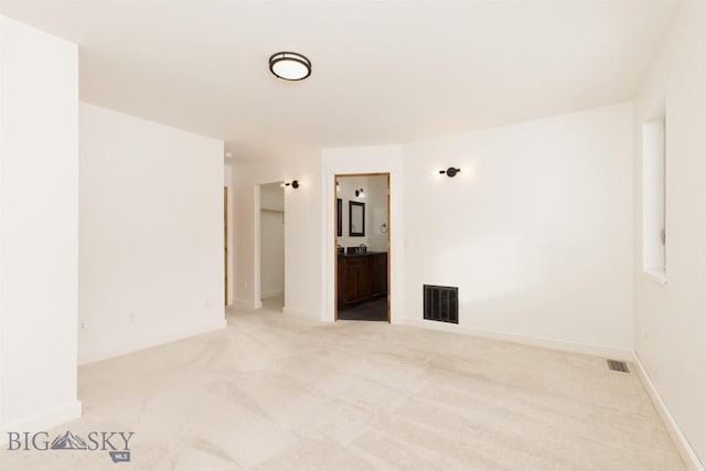 spare room featuring light colored carpet and baseboards