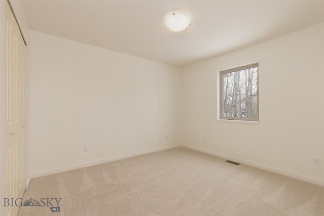 empty room featuring light carpet and baseboards