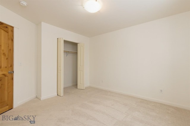 unfurnished bedroom featuring light colored carpet, baseboards, and a closet