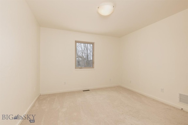 empty room featuring light colored carpet and baseboards