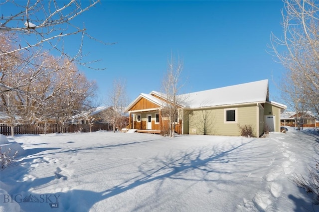 snow covered property with a porch and fence