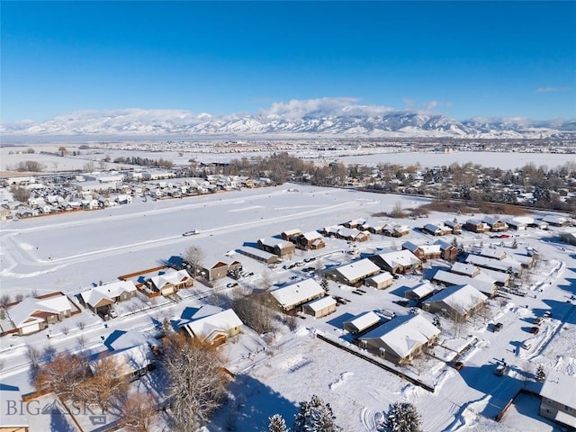 snowy aerial view featuring a mountain view and a residential view