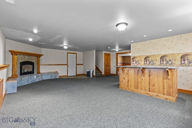 3450 W Hollyhock Dr, Belgrade, MT 59714 - unfurnished living room featuring carpet, baseboards, stairs, a tiled fireplace, and bar area