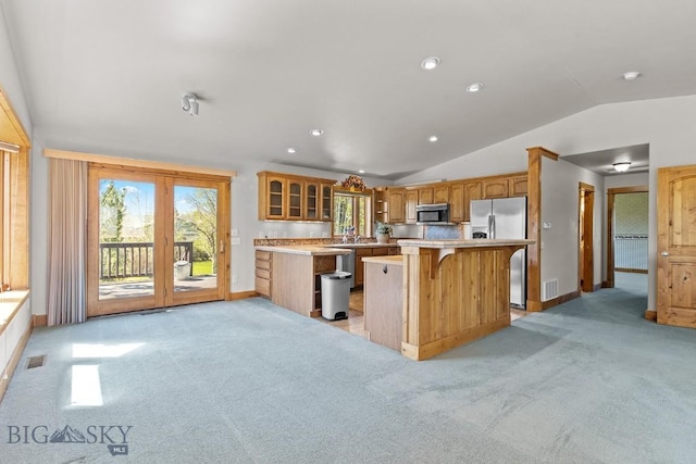 3450 W Hollyhock Dr, Belgrade, MT 59714 - kitchen with stainless steel fridge, lofted ceiling, light colored carpet, baseboards, and glass insert cabinets