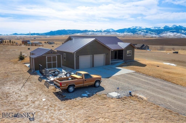 single story home featuring a mountain view, driveway, a storage unit, a garage, and metal roof