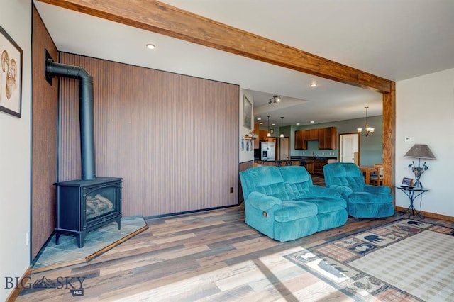 living room featuring wood finished floors, a wood stove, beamed ceiling, recessed lighting, and a chandelier