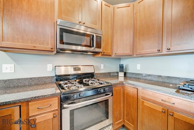 kitchen with appliances with stainless steel finishes and dark stone countertops