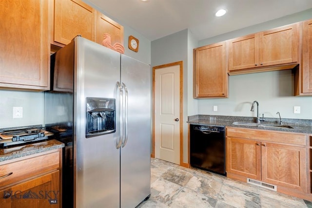 kitchen featuring dishwasher, a sink, stainless steel refrigerator with ice dispenser, dark stone counters, and stone finish floors