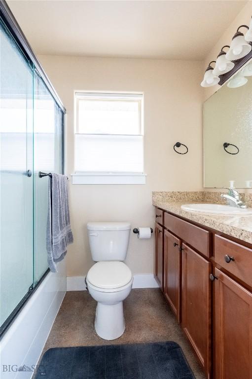 bathroom with vanity, toilet, baseboards, and bath / shower combo with glass door