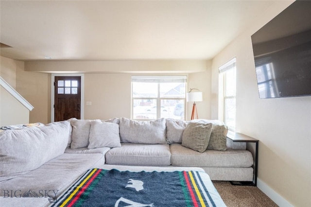 carpeted living area featuring healthy amount of natural light and baseboards