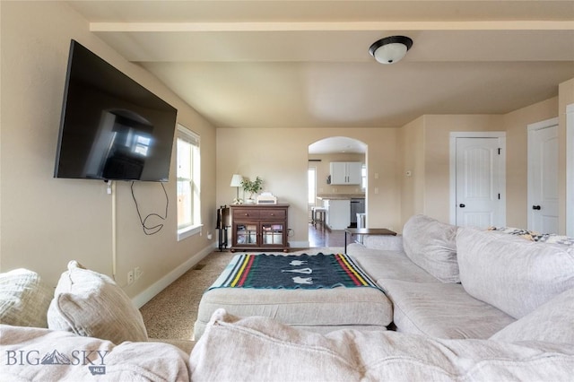 living room featuring arched walkways, baseboards, and light carpet