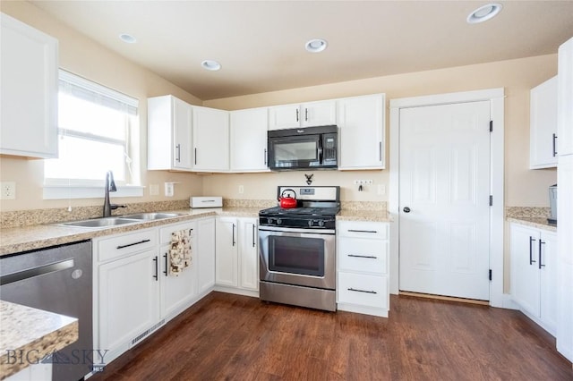 kitchen with appliances with stainless steel finishes, a sink, dark wood finished floors, white cabinets, and recessed lighting