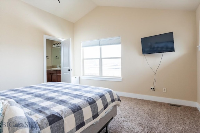 bedroom with carpet floors, a sink, lofted ceiling, baseboards, and connected bathroom