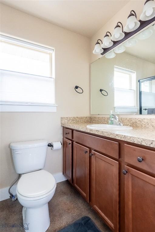 bathroom featuring vanity, toilet, baseboards, and a shower with shower door