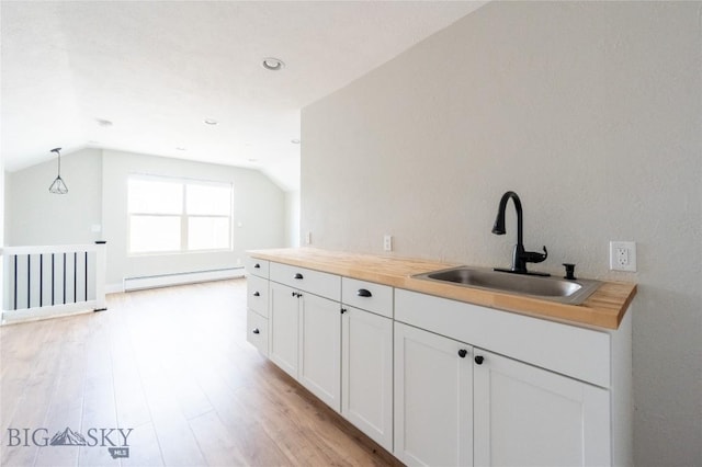kitchen with a sink, a baseboard heating unit, lofted ceiling, light wood-style floors, and white cabinetry