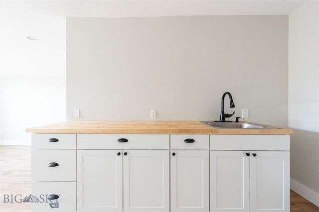bar with a sink, light wood-style floors, and baseboards