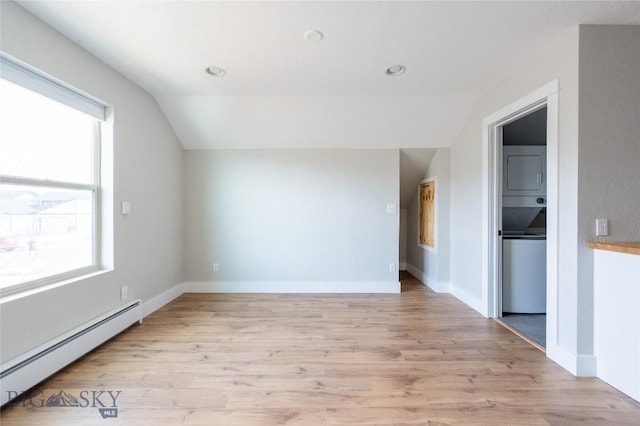 bonus room featuring stacked washing machine and dryer, baseboard heating, lofted ceiling, light wood finished floors, and baseboards